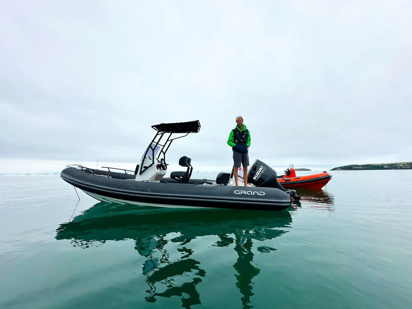 An instructor standing on a RIB powerboat on calm water off Abersoch