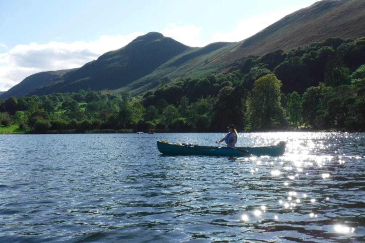 person canoeing on calm stream