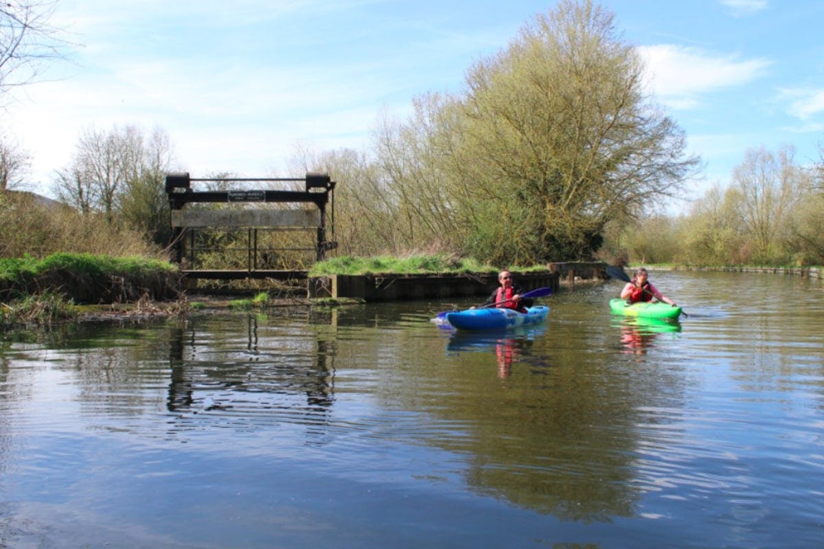 two people kayaking on calm stream