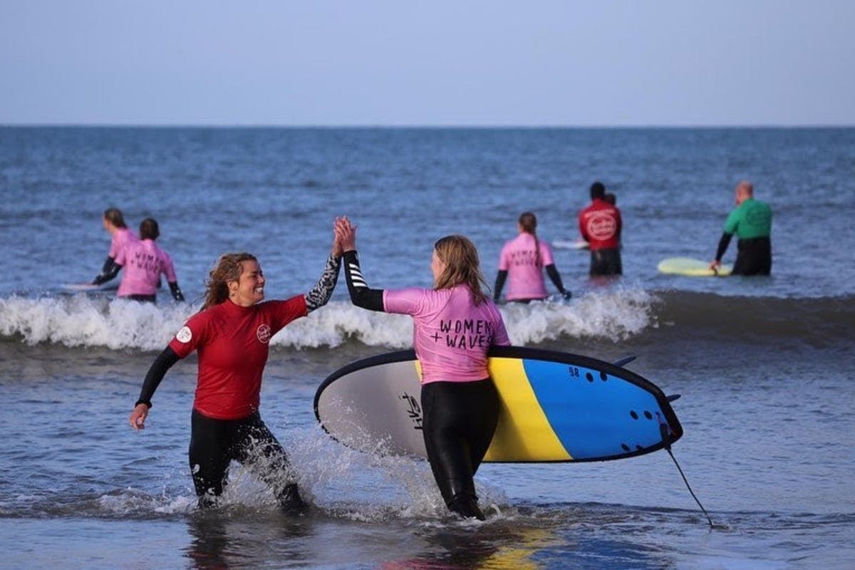 women and waves high five