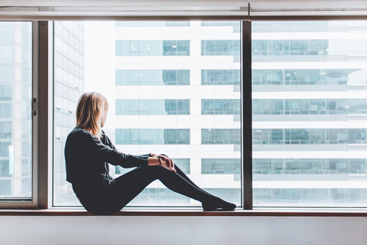 person looking out of a window in a city