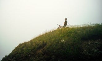 man looking out over hill on mountain bike