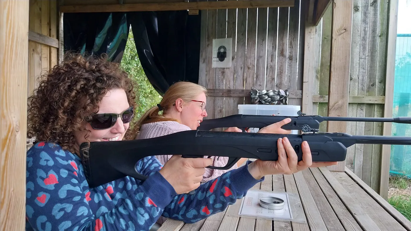 Two women aiming air rifles on the shooting range at UK Active Outdoors