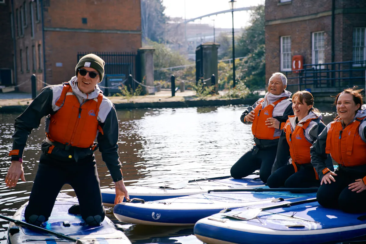 An instructor and three paddlers kneeling on paddleboards on the canal at Victoria Quays in Sheffield