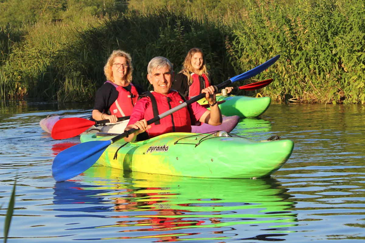 Three people paddling kayaks on the River Stort near Sawbridgeworth in evening sunshine