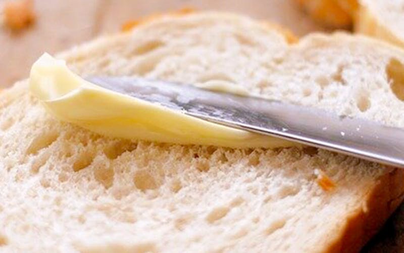 Epicurean Butter being spread on bread with a knife.