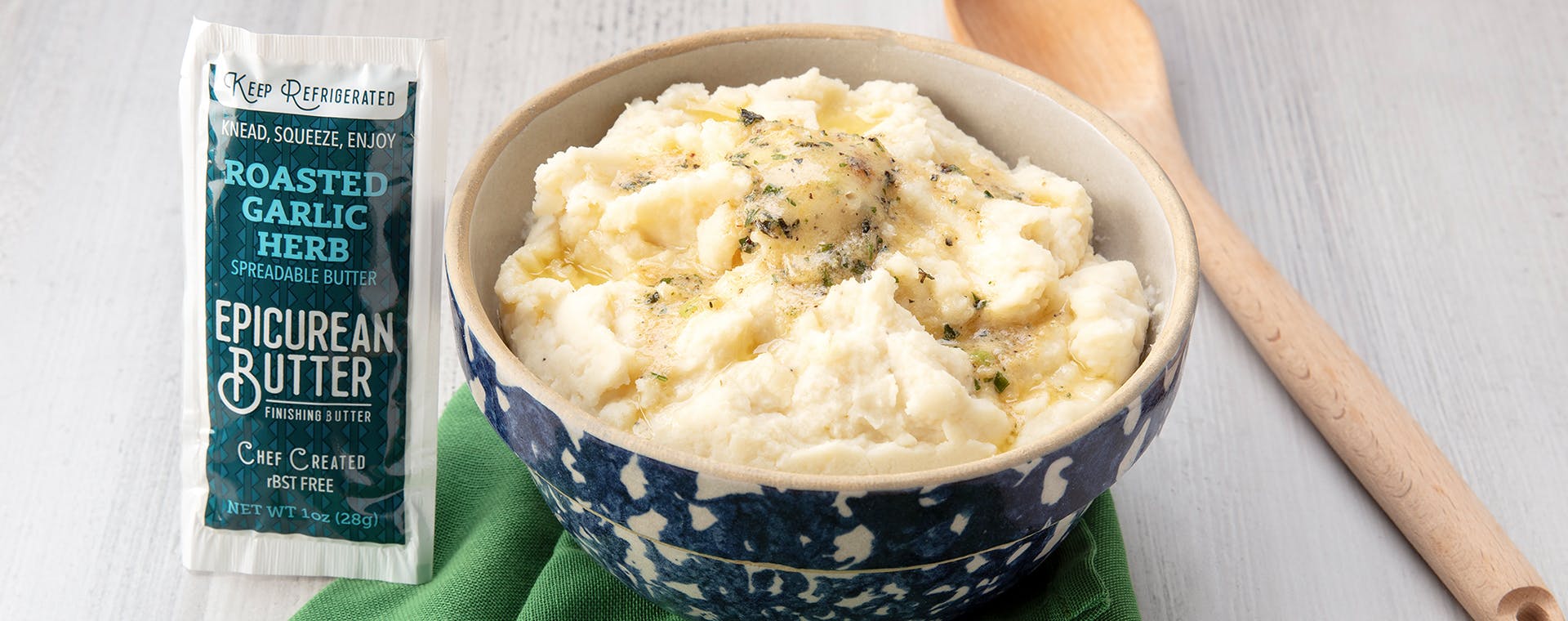 Bowl of mashed potatoes and 1oz squeeze packet of Epicurean Roasted Garlic Herb Butter.