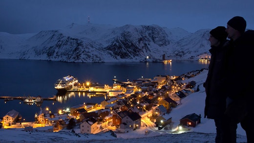 Par tittar ut över ett kvällsupplyst Honningsvåg i Norge. Foto: Ulrich Dajek/Hurtigruten