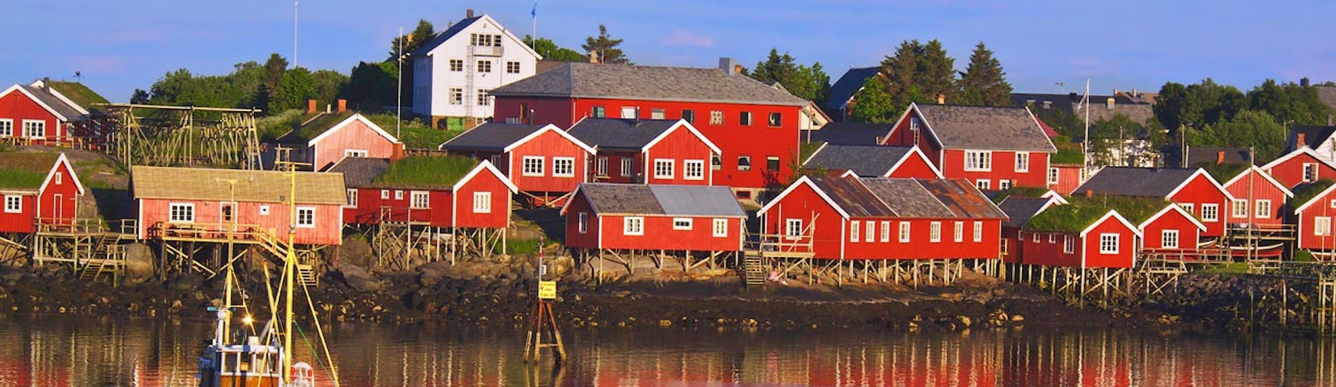 Hus i solen vid vattnet på Svalbard.