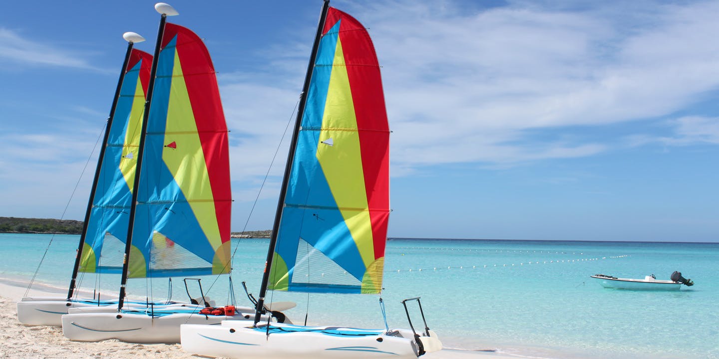 Små segelbåtar med färgglada segel på stranden på Half Moon Cay, Bahamas.