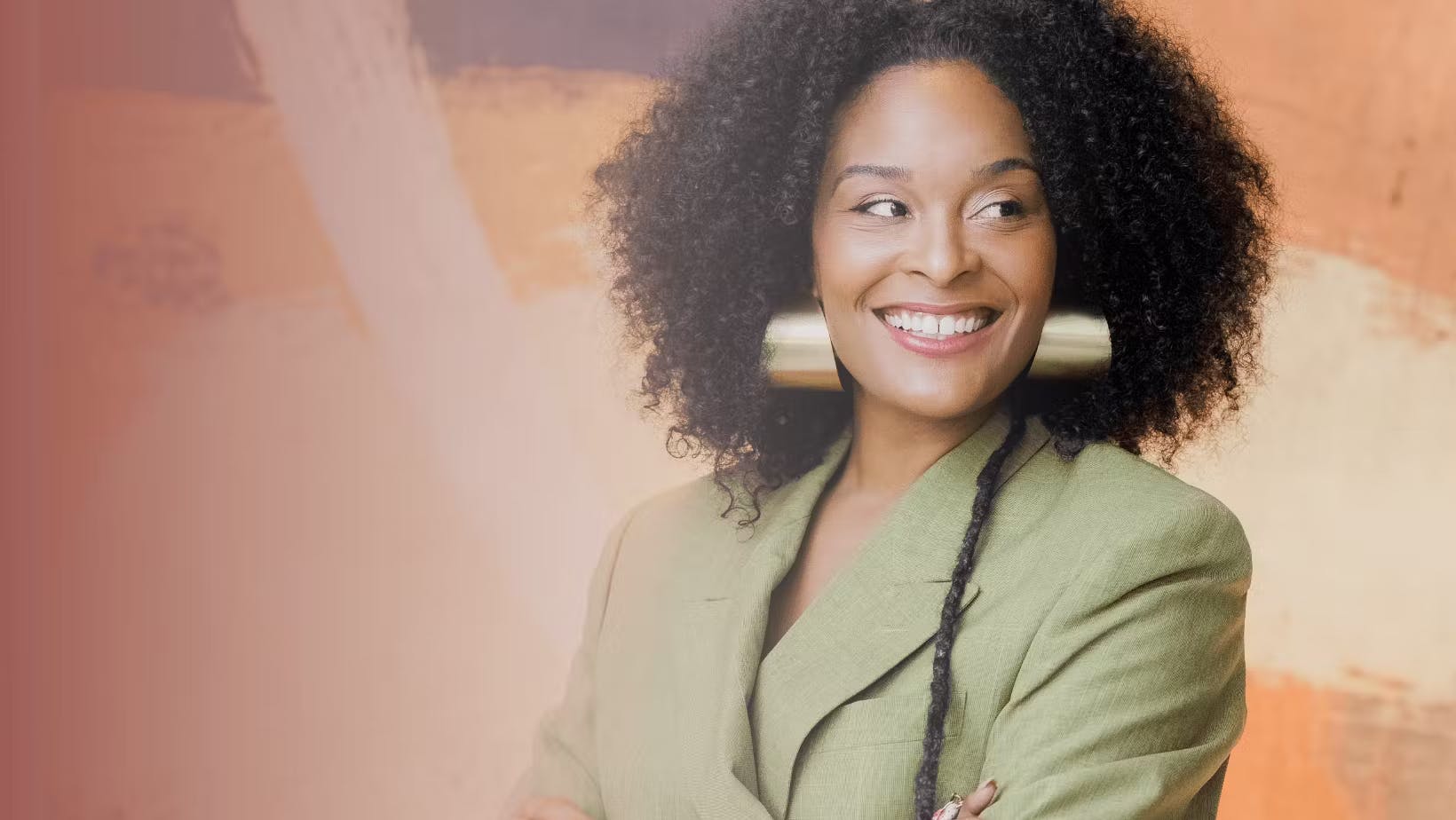 Erin Patten, wearing large gold earrings and a light green blazer, smiles while looking to the side. The background features abstract earthy tones.