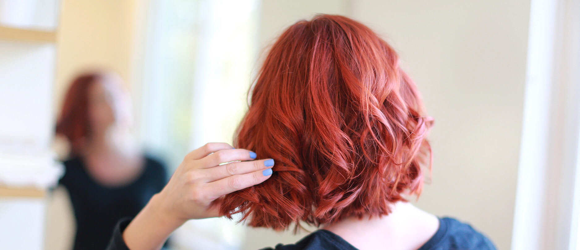 Woman with esalon's custom red hair color looking in mirror
