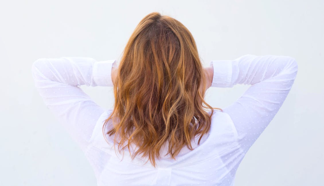 Image of esalon client back of head shot featuring trending custom hair color apple cider fireball with deep blonde copper color