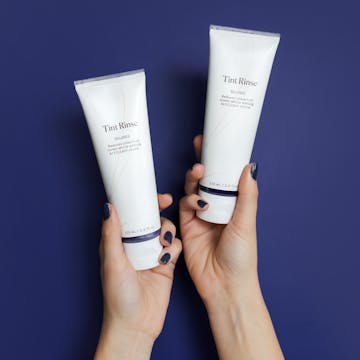 Image of hands holding two bottles of eSalon's Tint Rinse to enhance or neutralize hair color. 