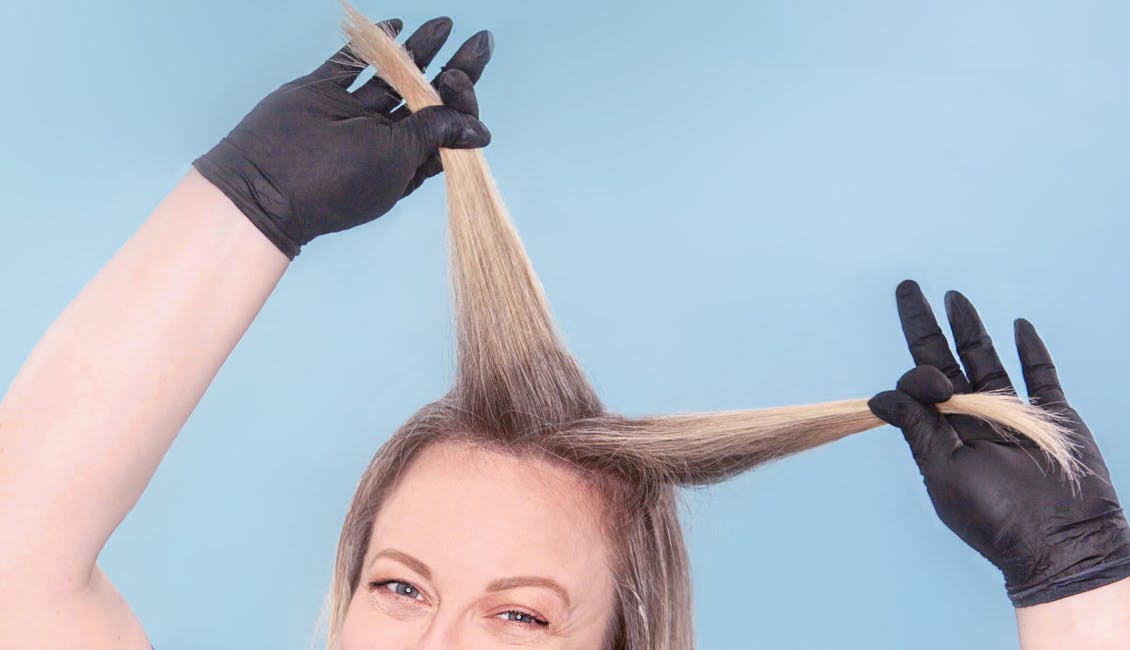 Image of esalon colorist separating her hair into sections before highlighting her side bangs with light set home balayage kit