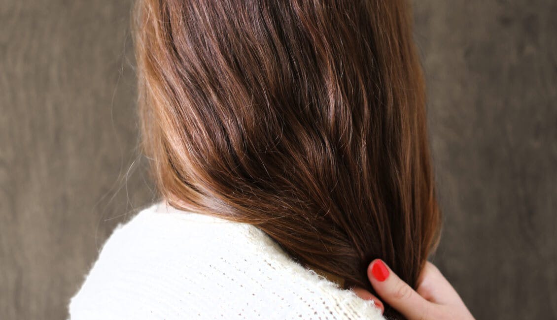 Image of woman's back of head brunette hair color with hand in hair