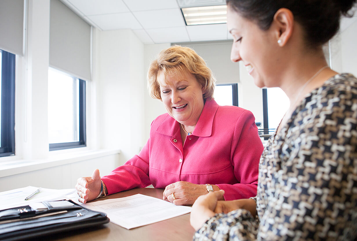 Image of CancerCare's CEO Patricia J. Goldsmith sitting at a desk with her employee looking over a document
