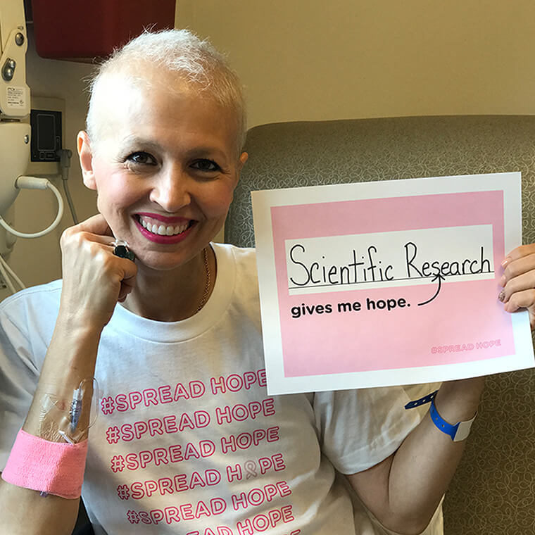 Image of esalon client chiara d'agostino in a hospital bed holding an a paper that says 