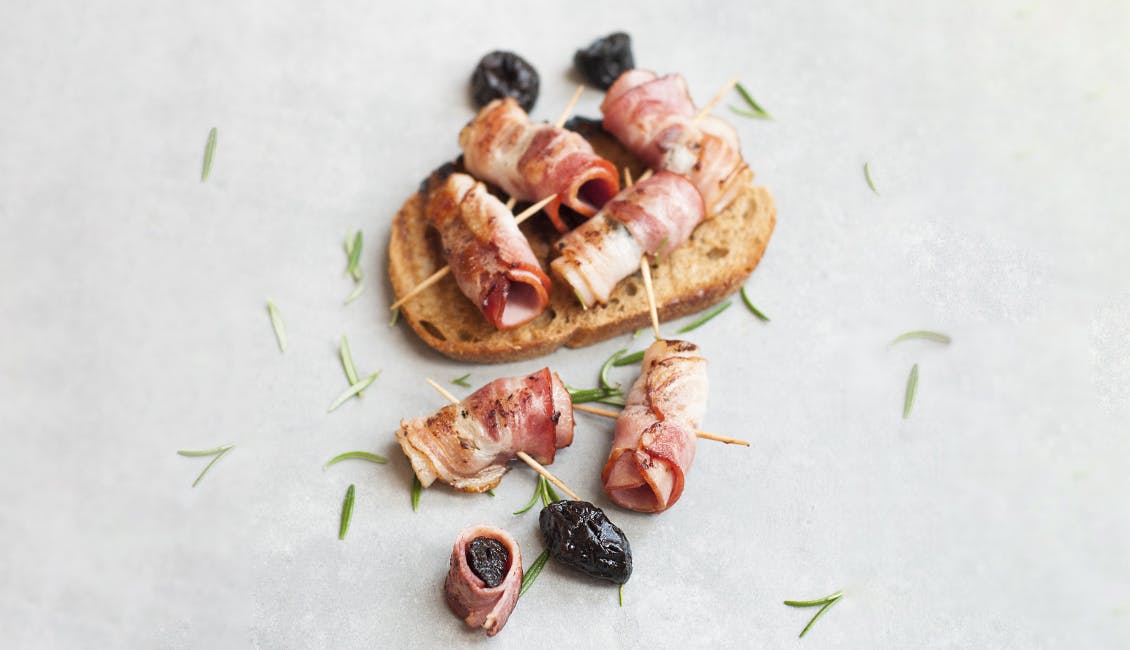 Dates wrapped in bacon and a piece of bread on the side. 