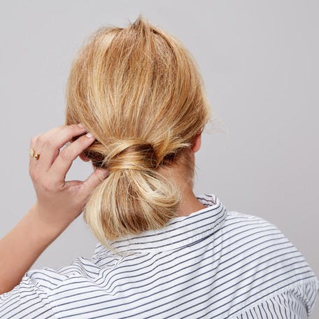 Image of esalon client renee's back of head shot with blonde hair and highlights in a low wrap-around bun updo in this how to article featured in color mastery