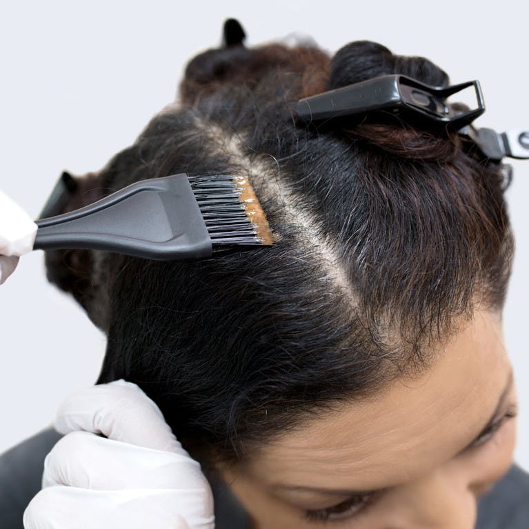 Image closeup of woman's roots as she colors her hair at home with eSalon's custom color set