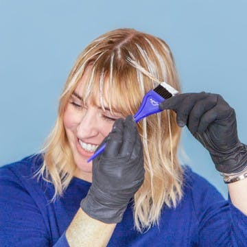 Image of esalon colorist highlighting her bangs with gloves on using Light Set balayage highlights