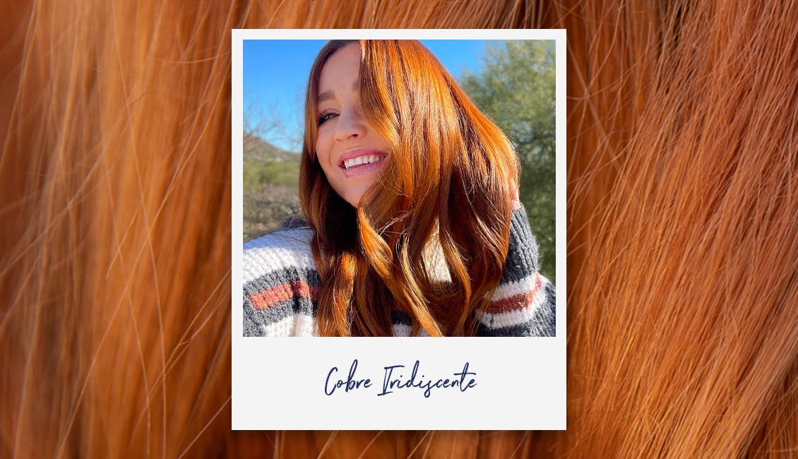 Woman smiling with flowing vibrant red hair outside.