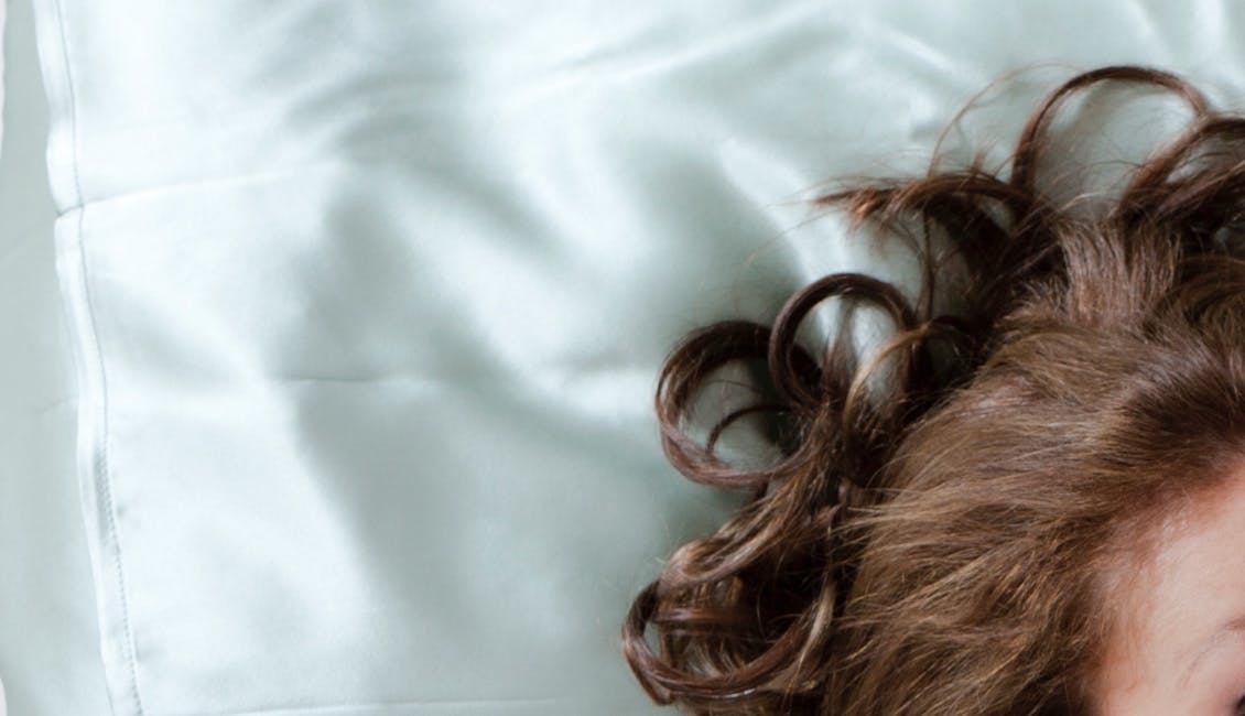 Woman lying on a silk pillowcase to reduce hair frizz