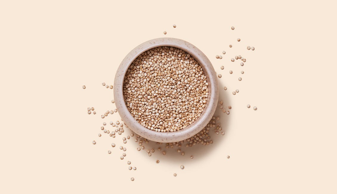 A bowl of Quinoa with individual granules sprinkled around it