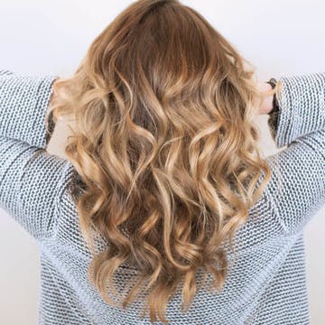 Image of blonde woman with beautiful custom hair color as the feature for esalon's trending hair color article