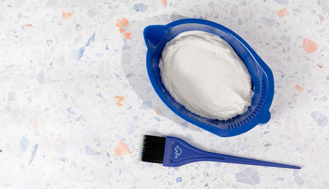 An image of an eSalon blue Coloring Bowl filled with hair color formula and a blue Color Tint Brush ready for application.