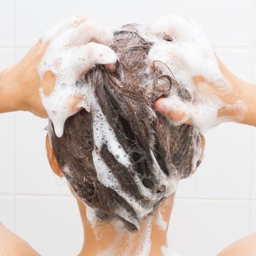 Image of woman in the shower washing her color-treated hair. 