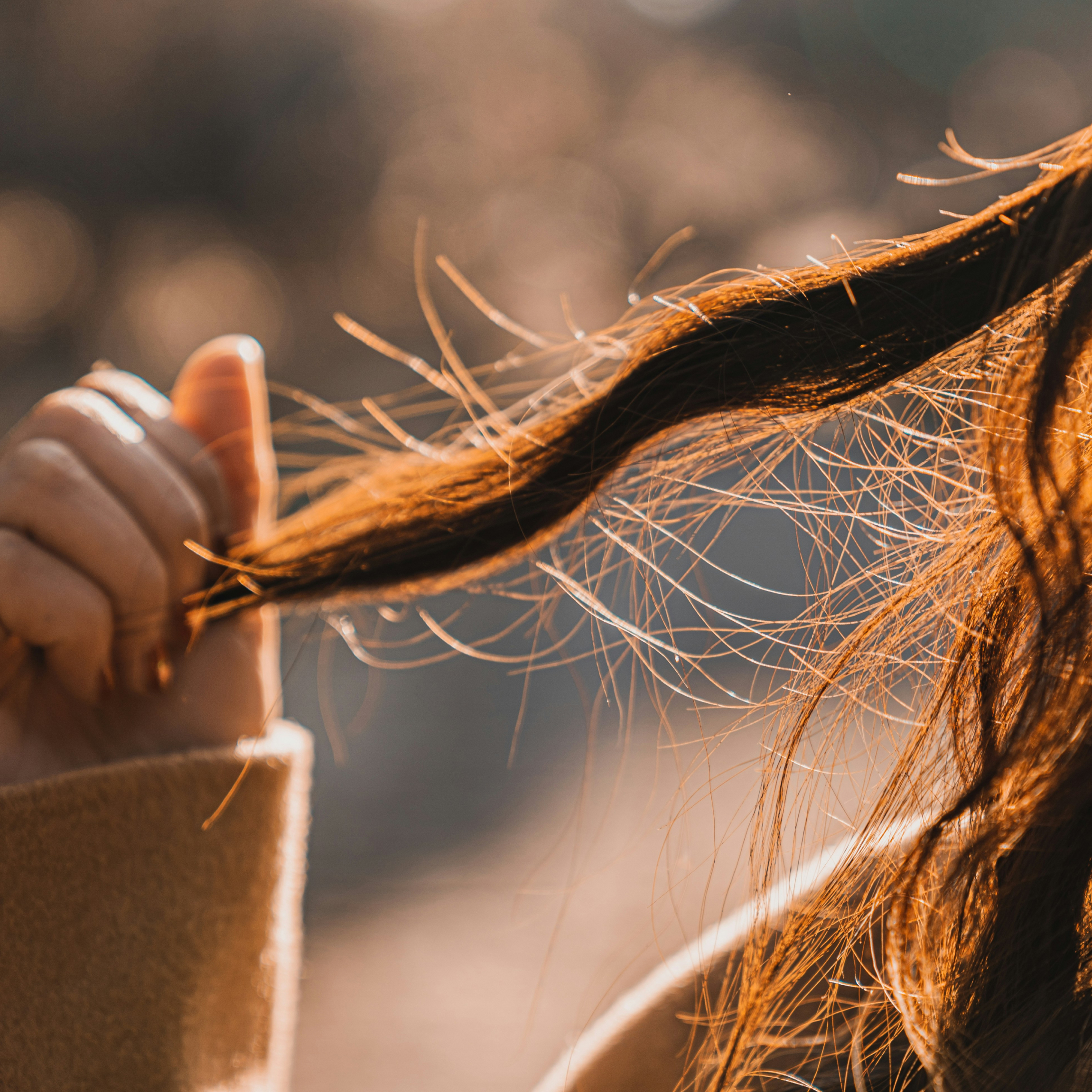 Woman with long hair holding onto a few strands. 
