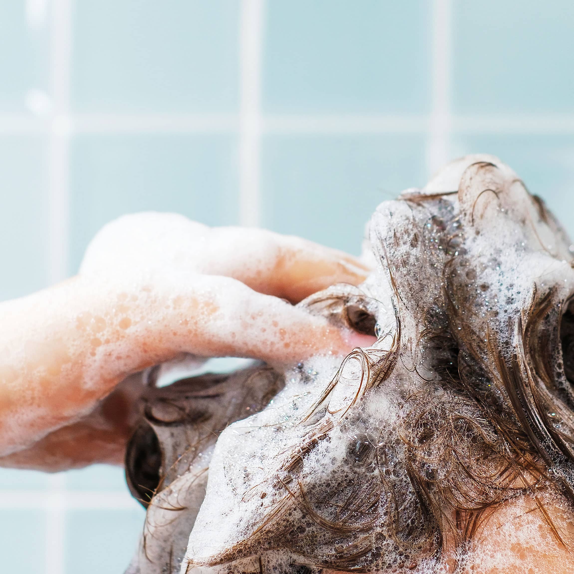 Person shampooing their hair with a lot of suds. 