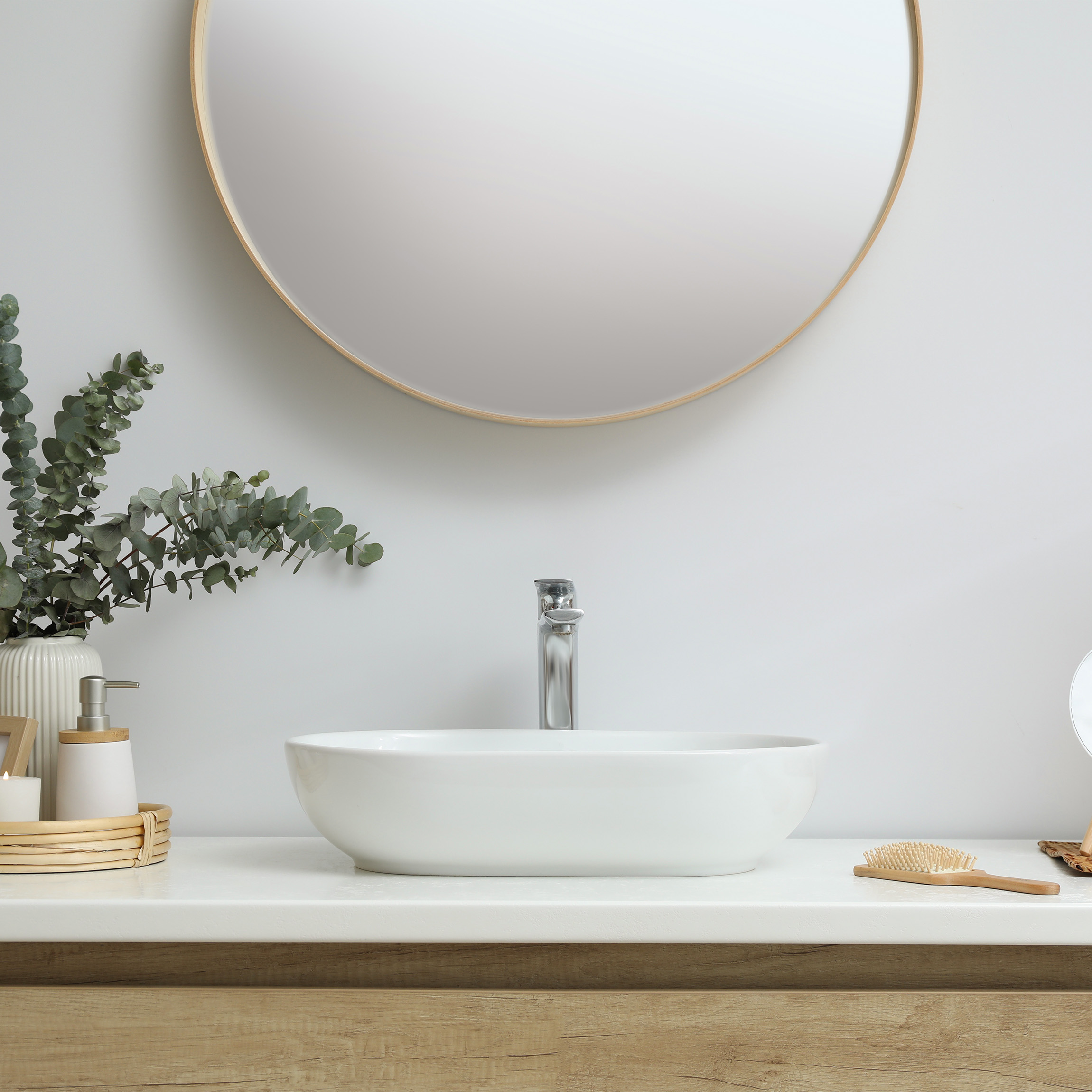 Very clean bathroom counter with bamboo accents and a bouquet of eucalyptus. 