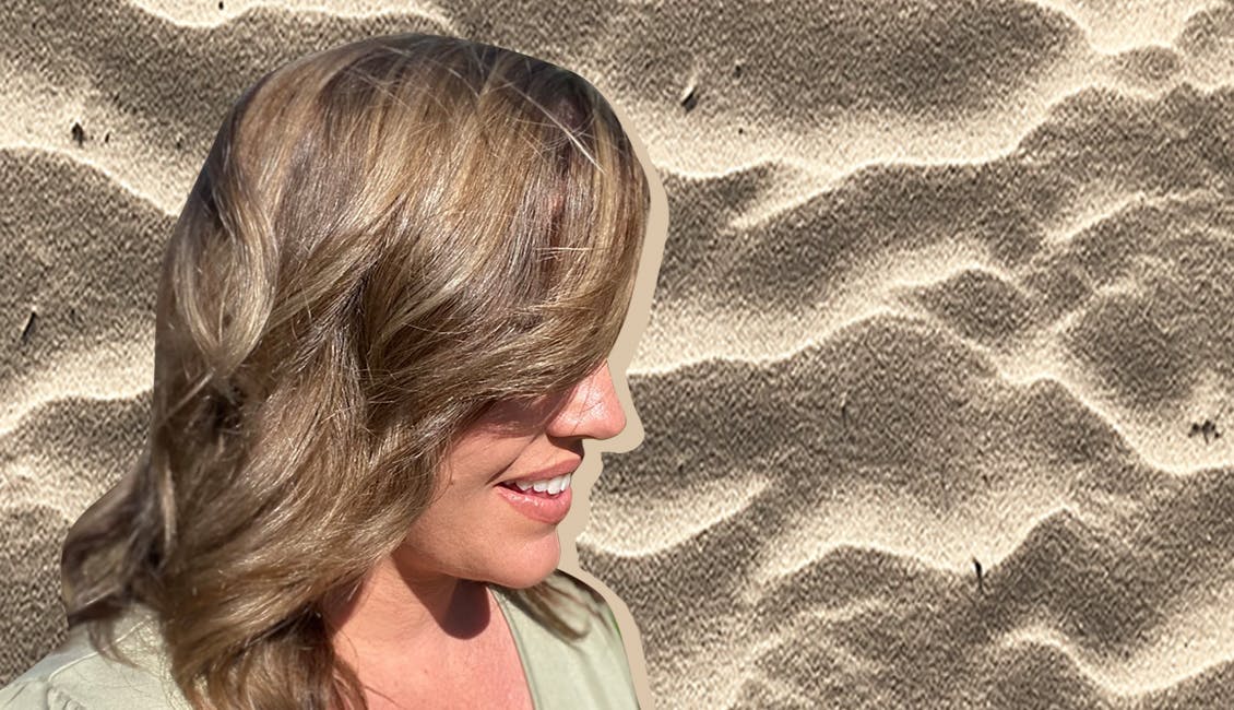 Woman with Sandy Blonde hair color and a beach in the background. 