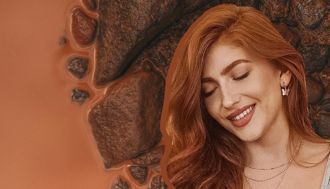 Woman with Burnt Sienna hair color and wet clay in the background. 