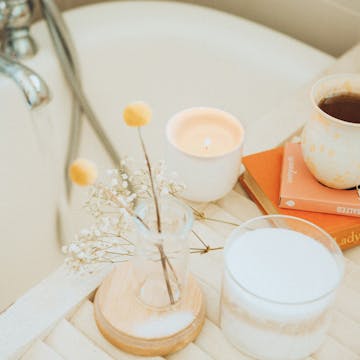 Bathtub with tea, books, and a candle nearby. 