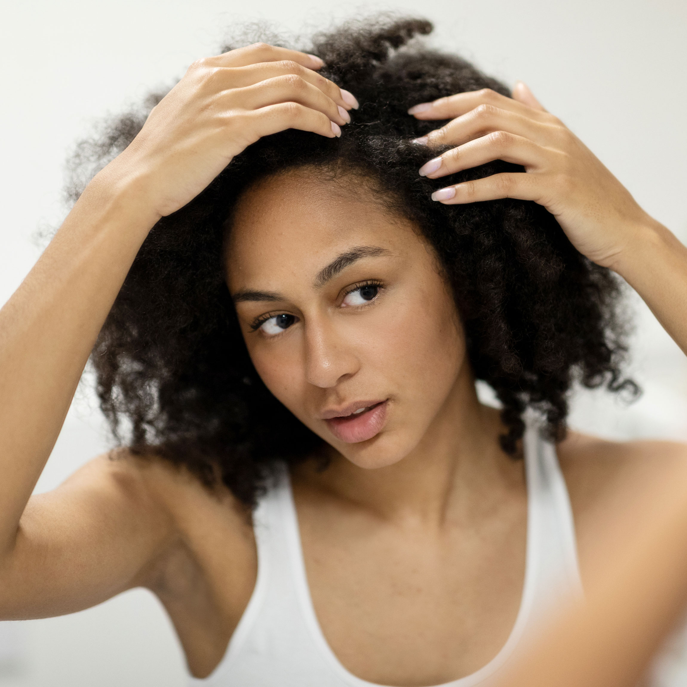 Woman looking for gray hairs in her hair. 