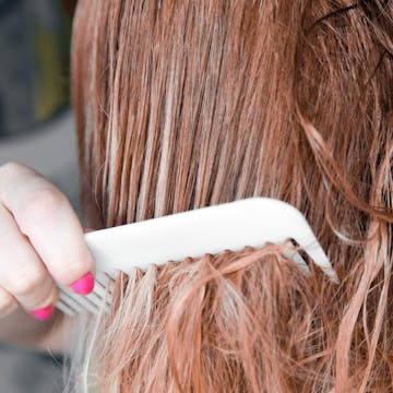 Woman combing through tangled hair.