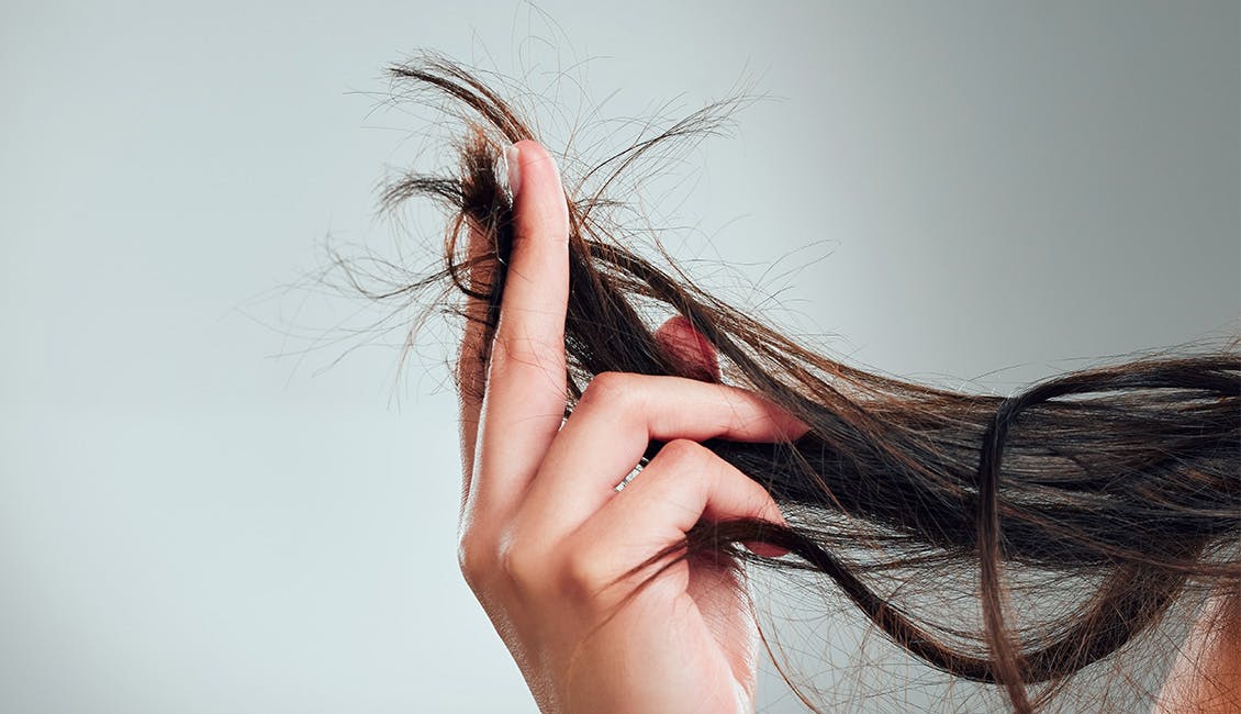 Woman examining the ends of her hair.