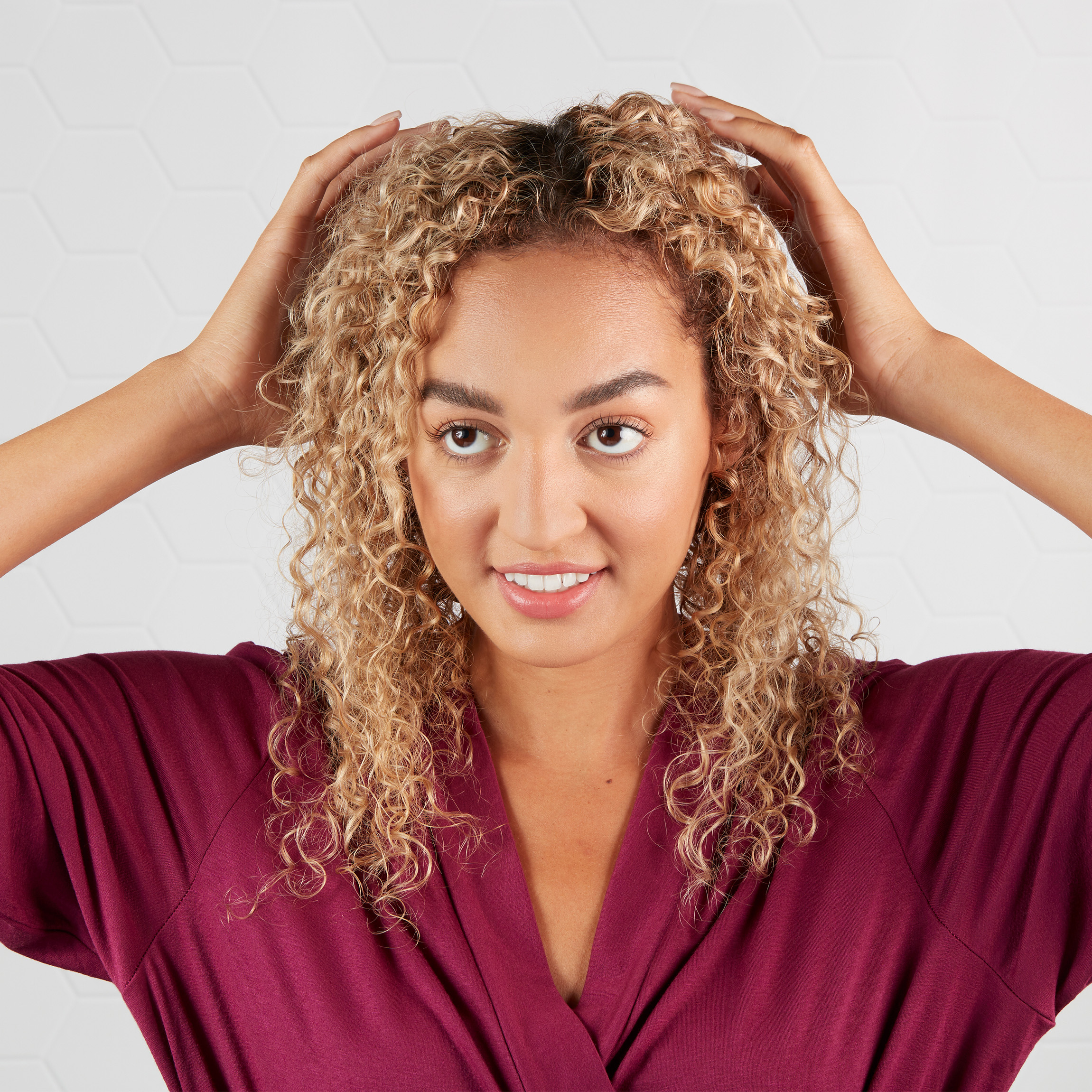 Woman with curly hair massaging her scalp.