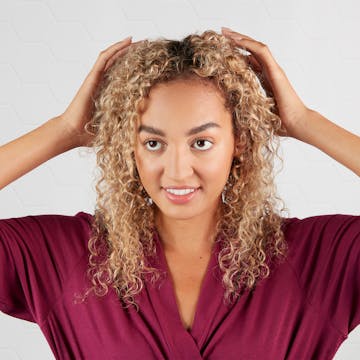 Woman with curly hair massaging her scalp.