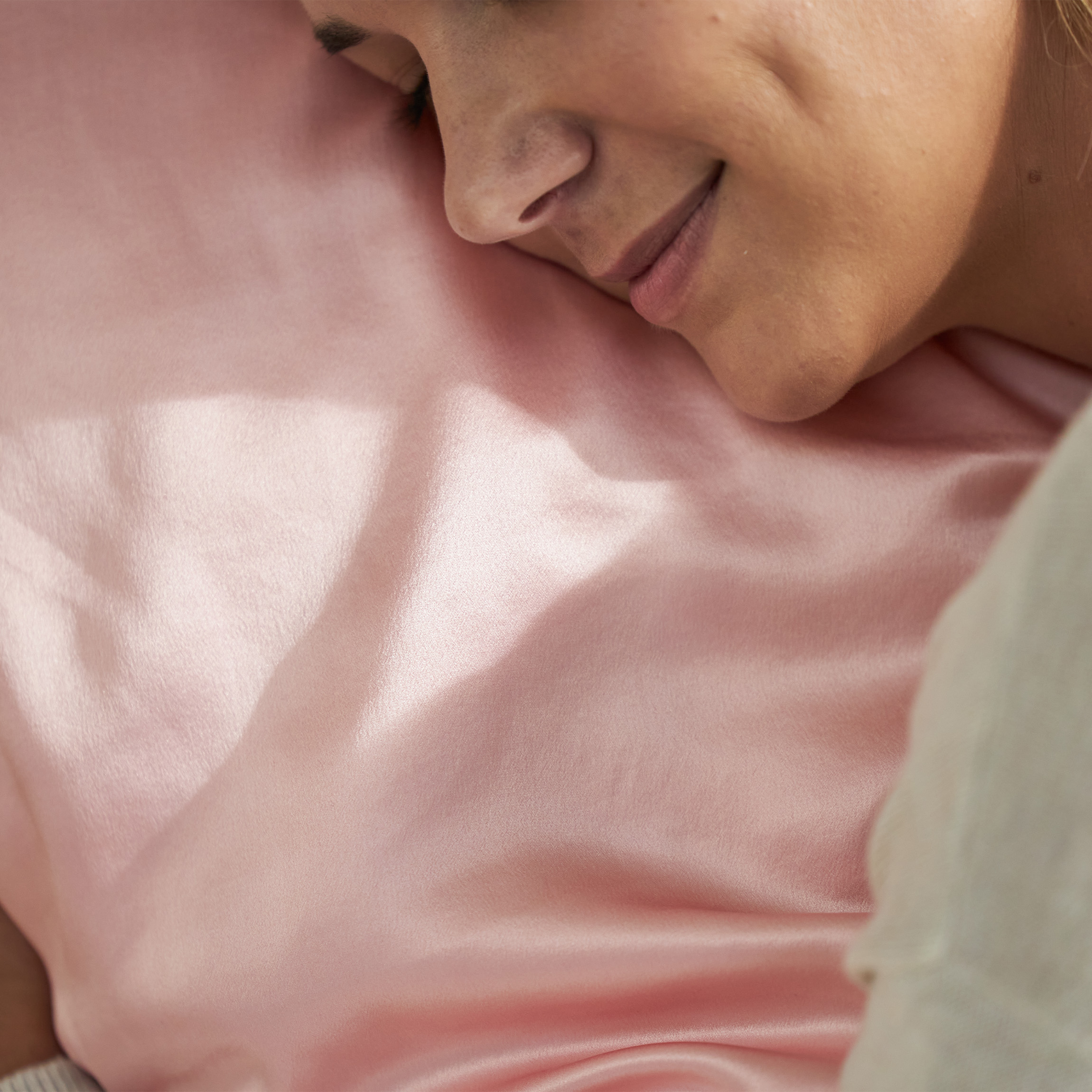 Woman sleeping on a pink silk pillowcase. 