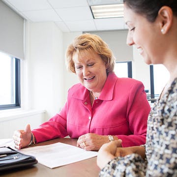 Image of CancerCare's CEO Patricia J. Goldsmith sitting at a desk with her employee looking over a document