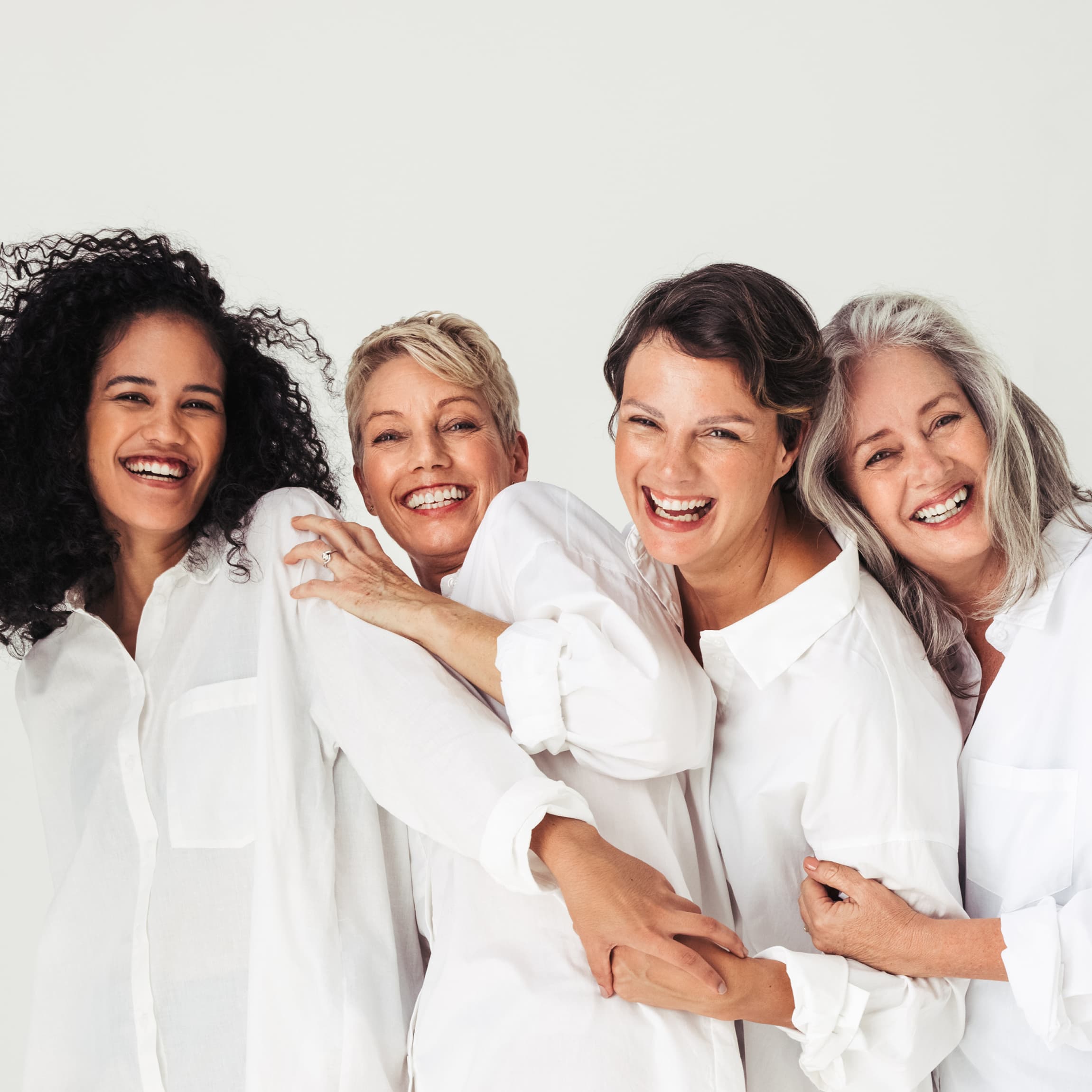 Four women with different hair colors are smiling and laughing.