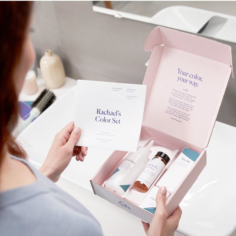 Woman unboxing customized home hair color set in bathroom
