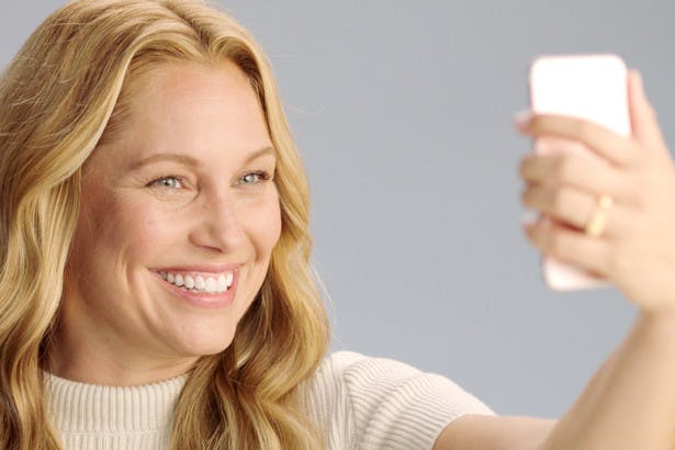 Image of blonde woman taking a selfie with her iPhone