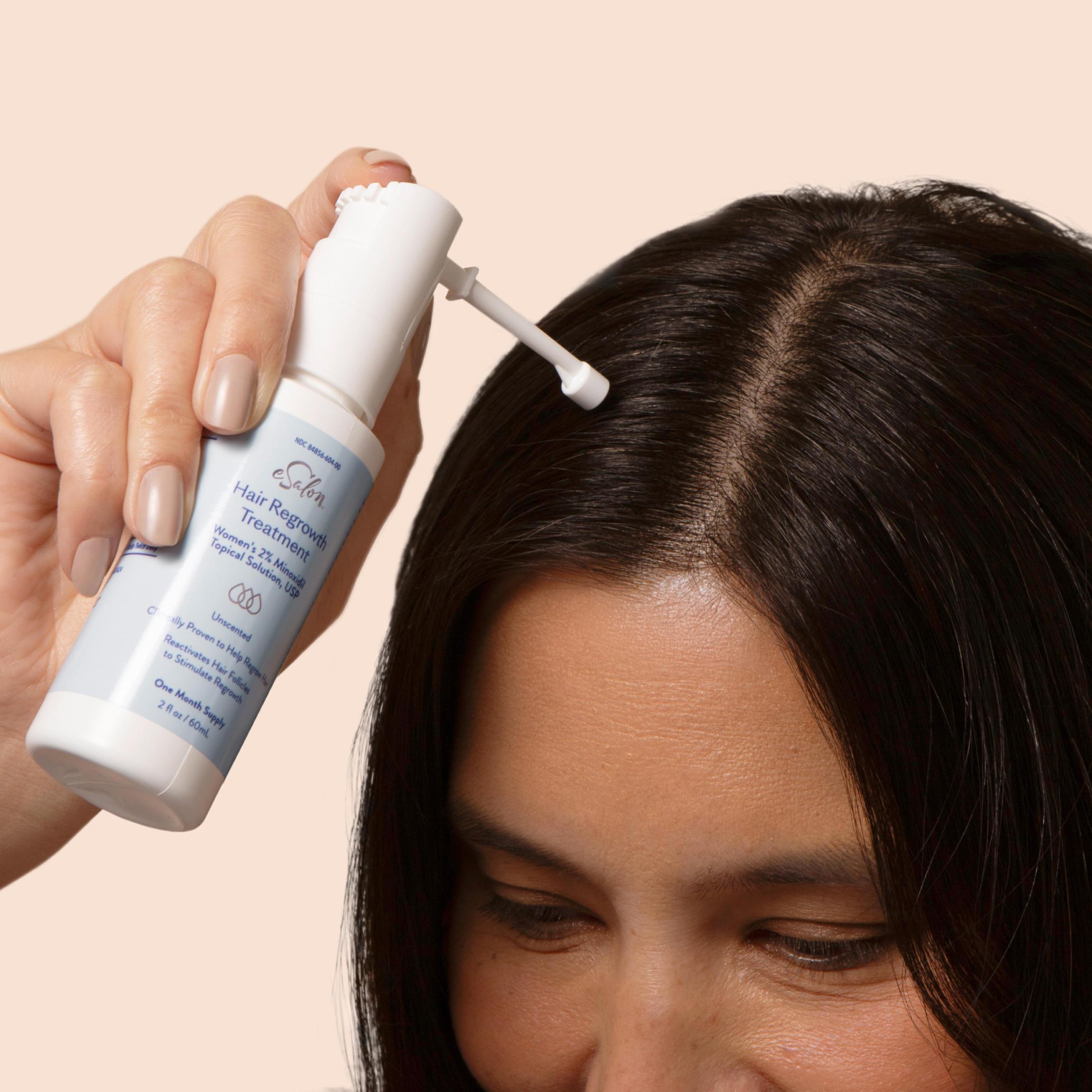 Woman applying the eSalon 2% Minoxidil Hair Regrowth Treatment to her scalp. 