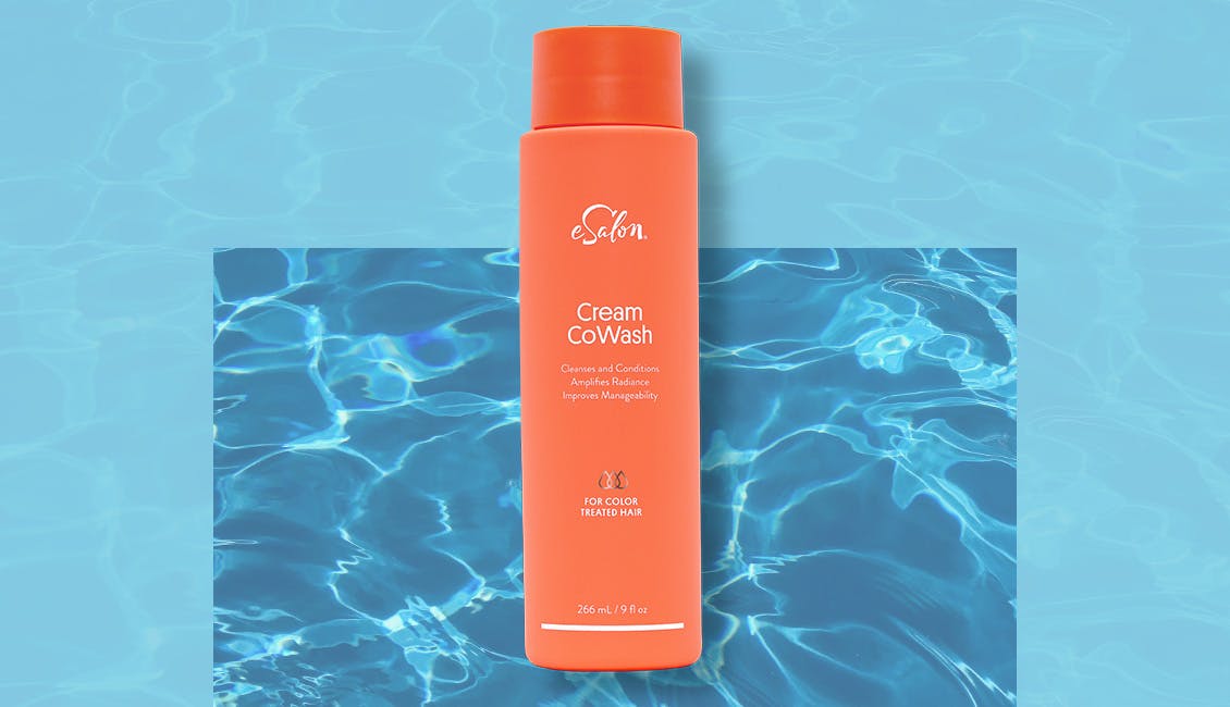 Bottle of cream cowash cleanser against a water background.